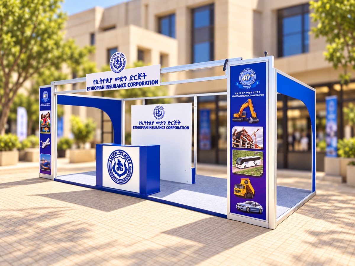 A blue and white corporate stand with a branded reception counter, a fascia with lettering and tall printed pillar panels, built on paving outside an office building