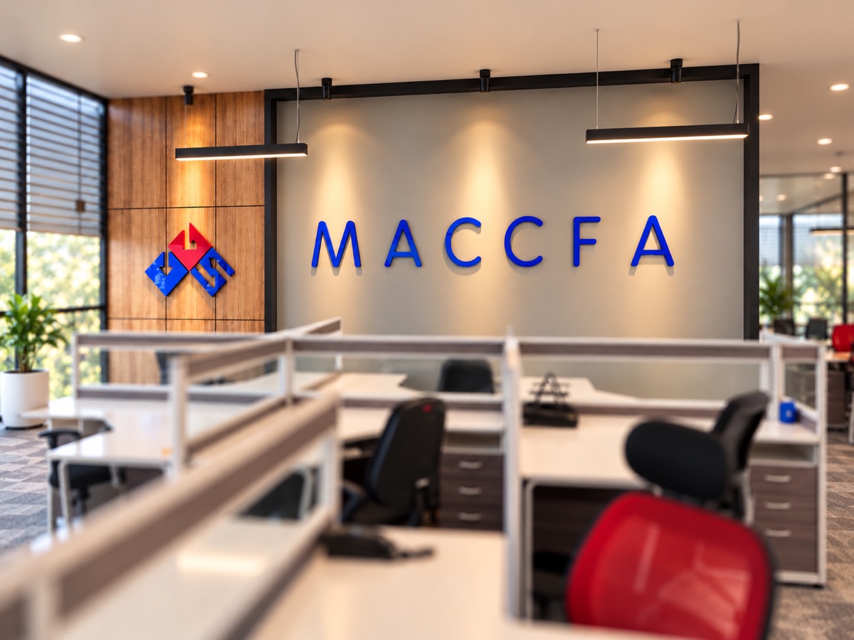 Raised blue acrylic letters and a red and blue logo on a grey feature wall, above open-plan office desks and chairs
