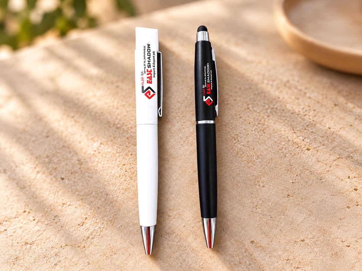 Two branded ballpoint pens, one white and one black, lying on a sunlit sandstone surface